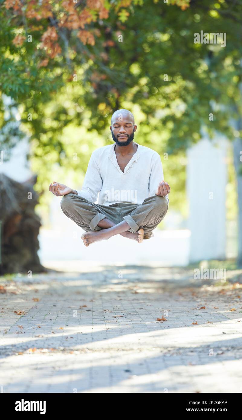 Yogas got him floating. Full length shot of a handsome young man levitating while meditating outside at the park. Stock Photo