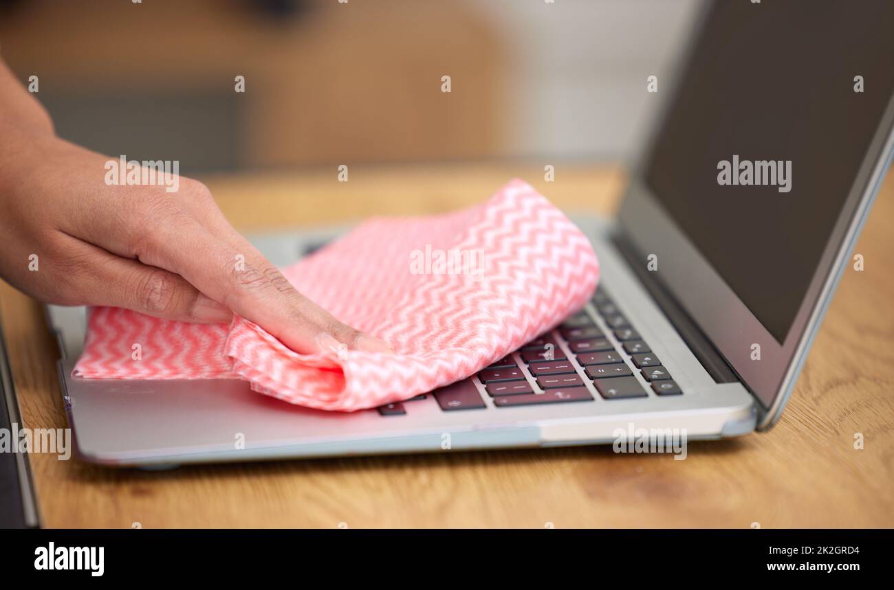 Getting in the crevices. Shot of a woman cleaning the dust from the laptop keyboard. Stock Photo