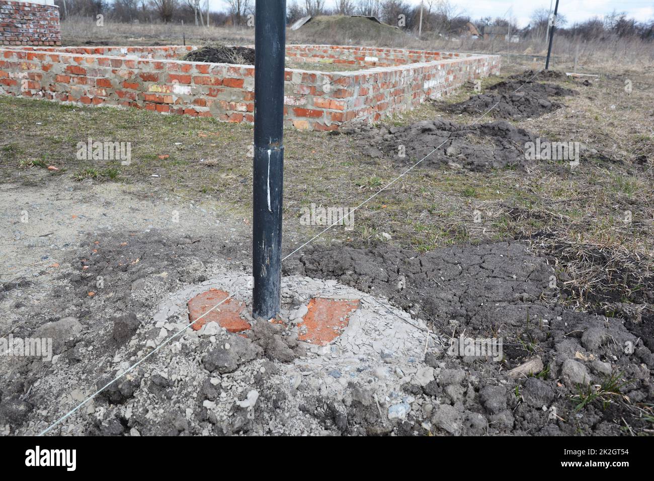 Digging holes for fence metal pillars concrete foundation Stock Photo