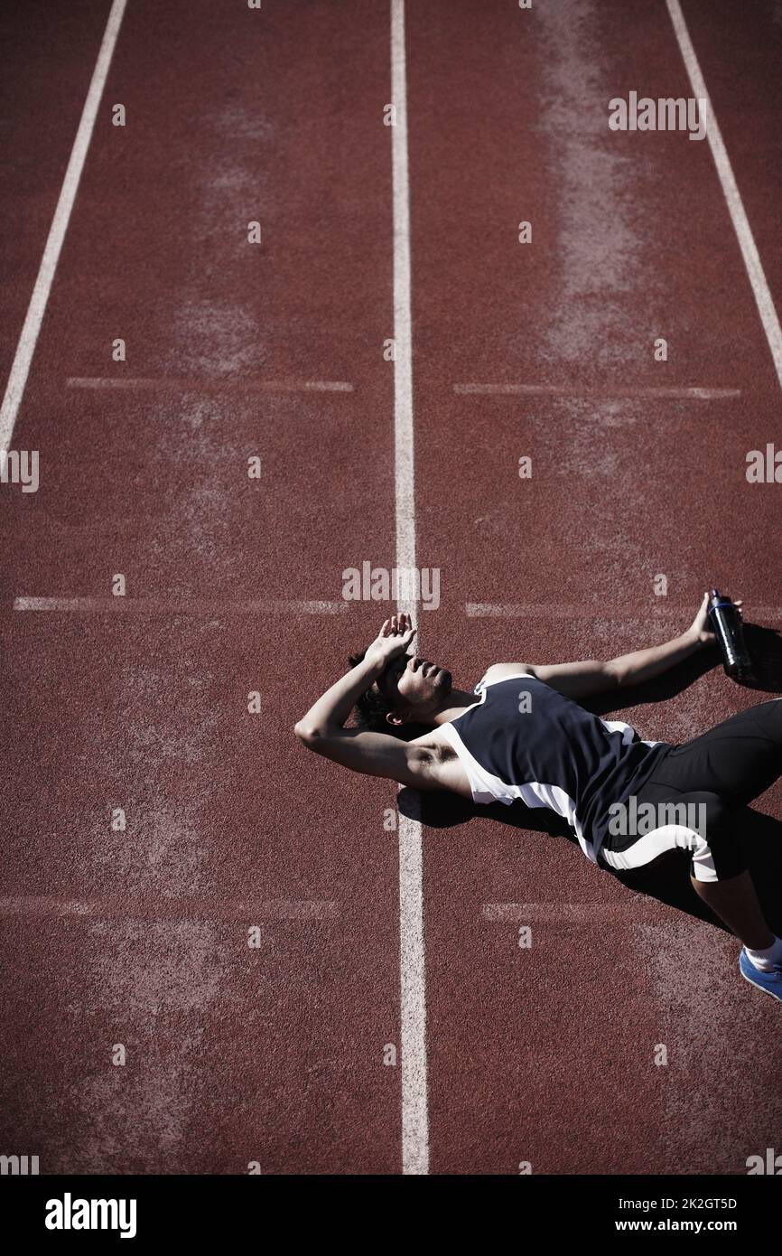 Life in the fast lane is tiring. A young runner lying down on the tartan track. Stock Photo