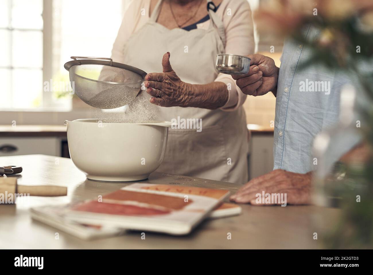 I always have help by my side. Shot of an unrecognizable couple baking together at home. Stock Photo