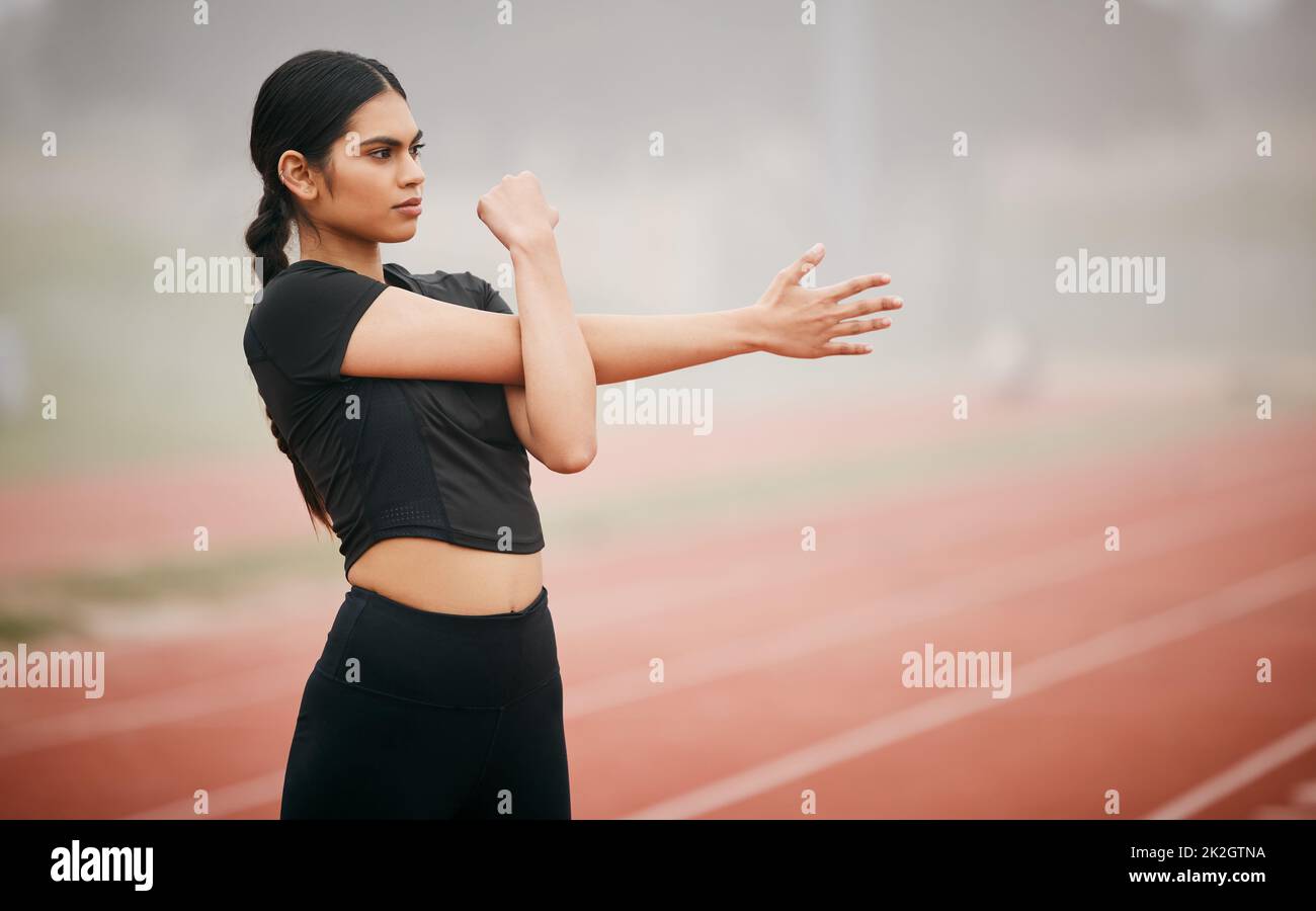 If youre confident, youll achieve anything you put your mind to. Shot of an athletic young woman stretching while out on the track. Stock Photo