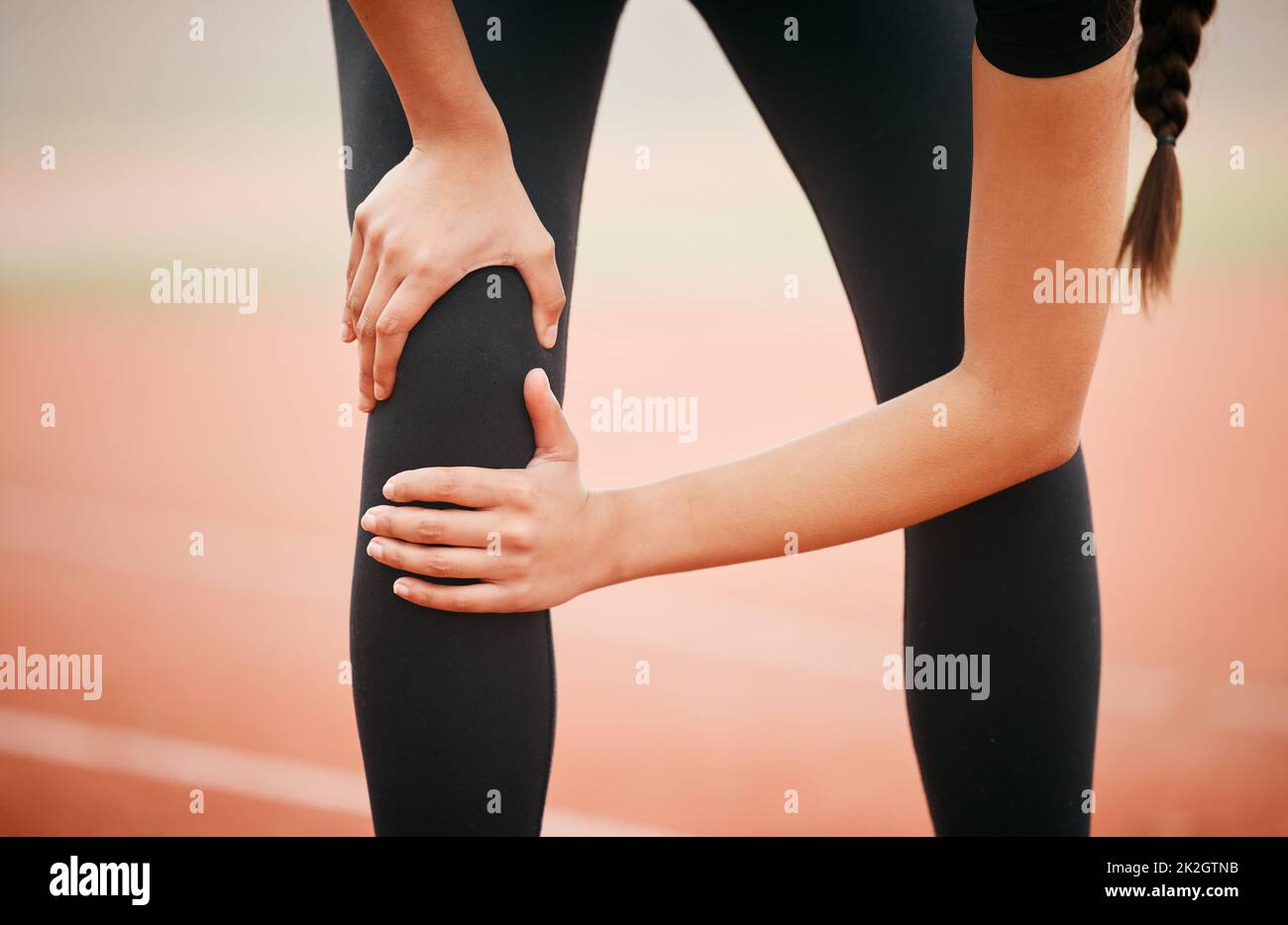 This injury happened at the worst possible time. Shot of an athletic young woman suffering from a sports injury while out on the track. Stock Photo