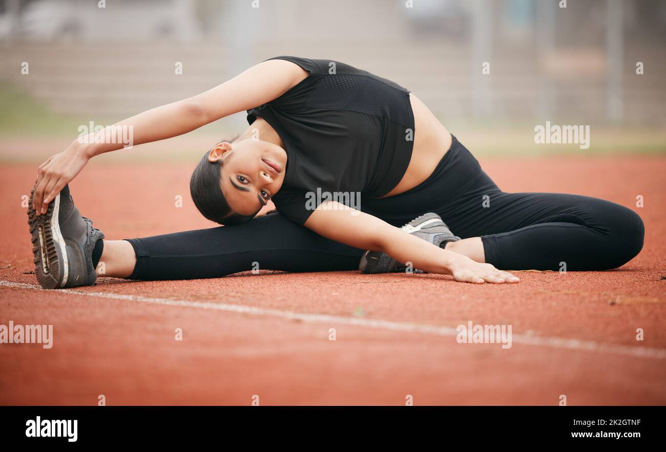 Im quite flexible. Shot of an athletic young woman stretching while out on the track. Stock Photo