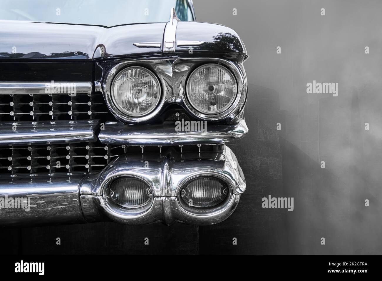 Front headlights of antique American road cruiser against blurred background, monochrome image Stock Photo