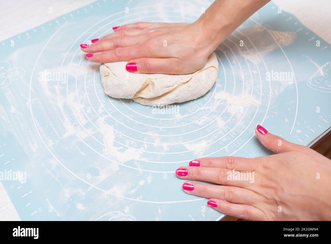 .Dough preparation, cooking at home. Female hands roll out the dough on a silicone mat. Stock Photo