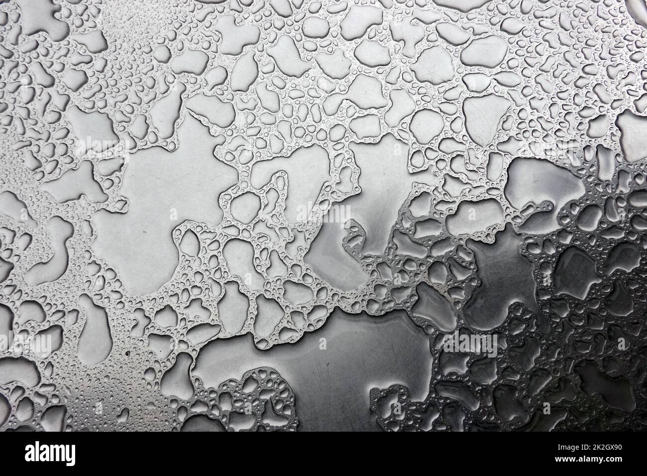 Regenwasser auf einem Bistrotisch bilden ein abstraktes Muster Stock Photo