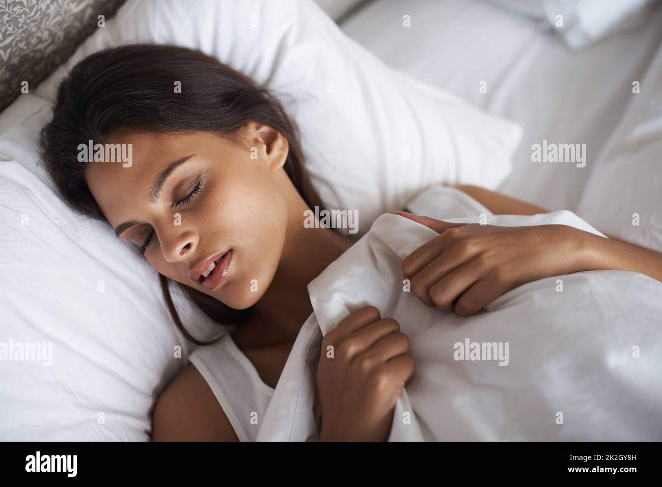 Far off in dream land. A beautiful young woman sleeping in her bed. Stock Photo