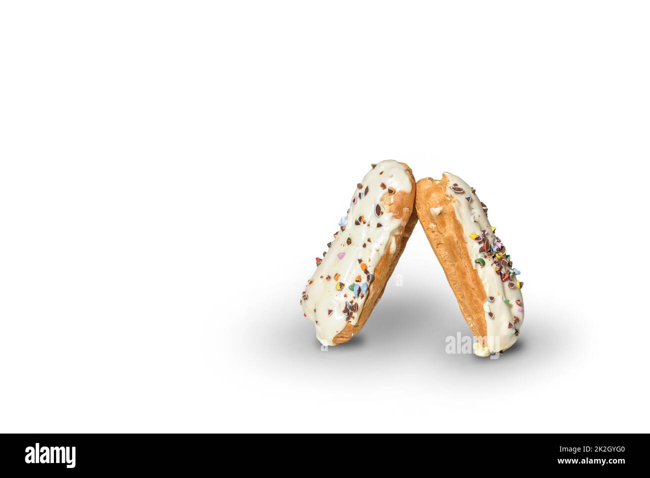 Two eclairs decorated with white chocolate icing and colorful baking sprinkles on a white background. Stock Photo