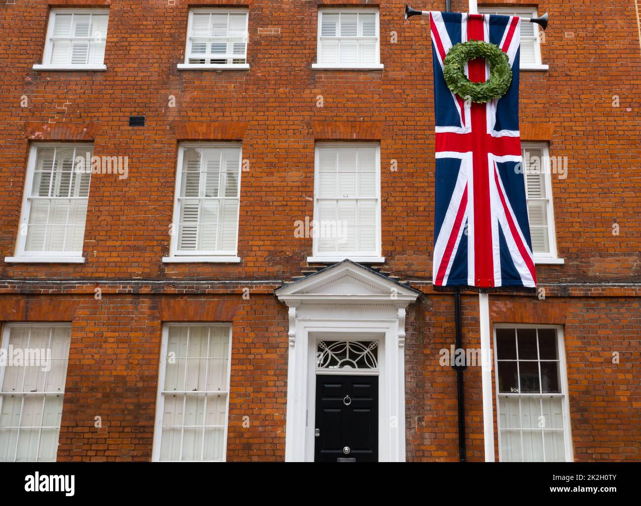 Union Jack flag with a floral wreath hanging at a house close to Windsor Castle on the death of Elizabeth II Stock Photo