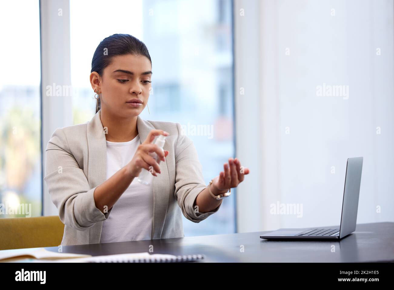 Living lifestyles of the wish-you-would. Shot of a young businesswoman sanitising her work station in a modern office. Stock Photo