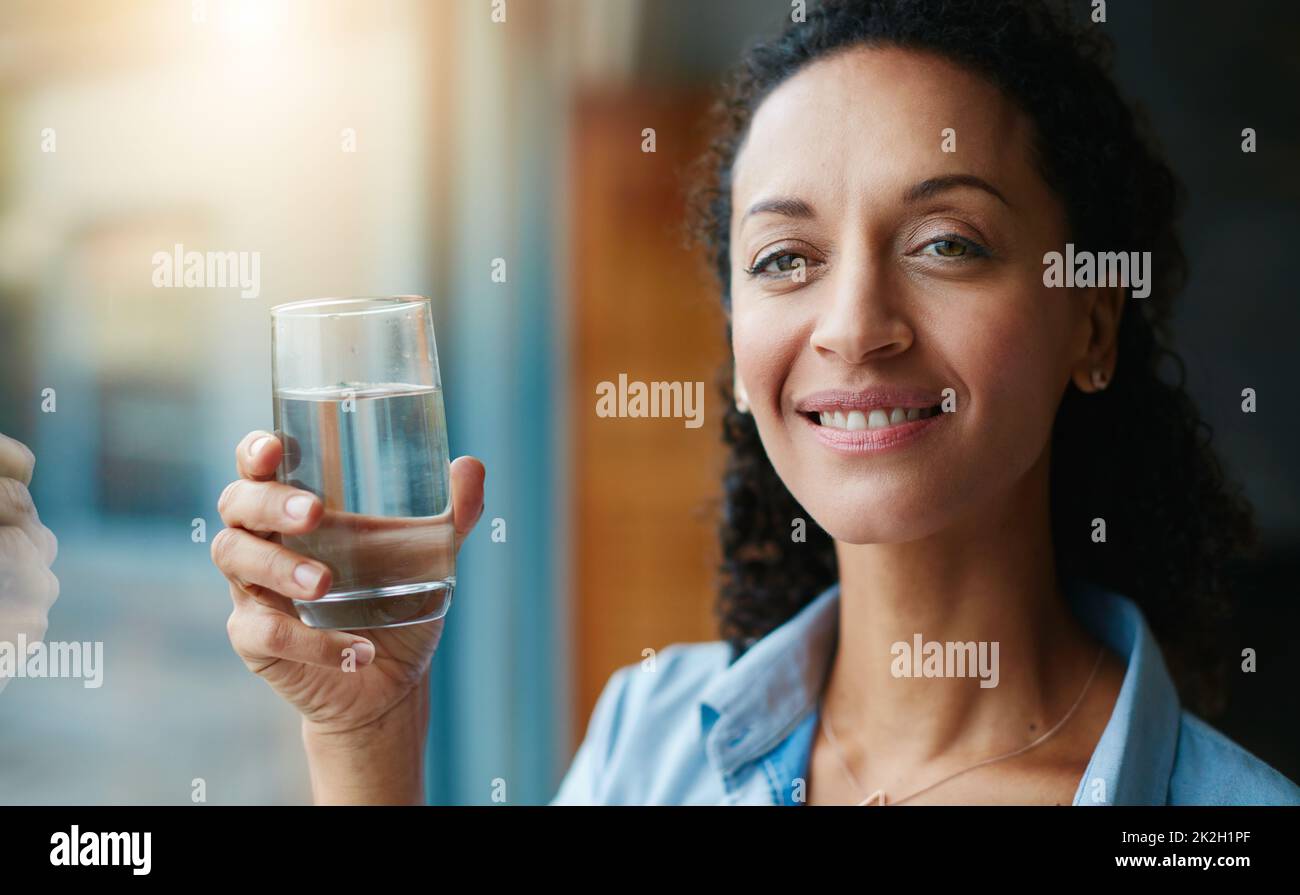 Working on my daily water goal. Portrait of a woman drinking a glass of