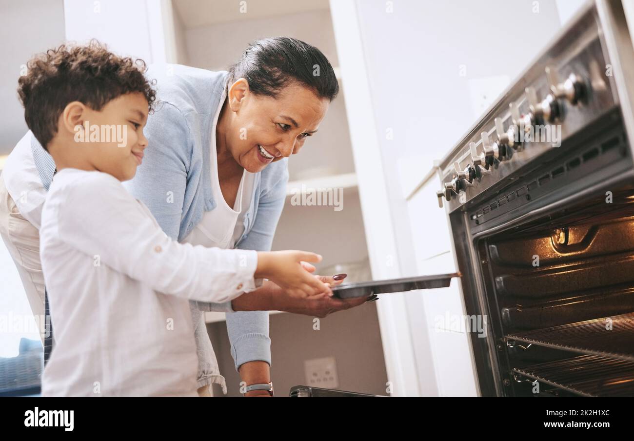 Are you excited to see what you made. Shot of a mature woman helping her grandchild safely open the oven at home. Stock Photo