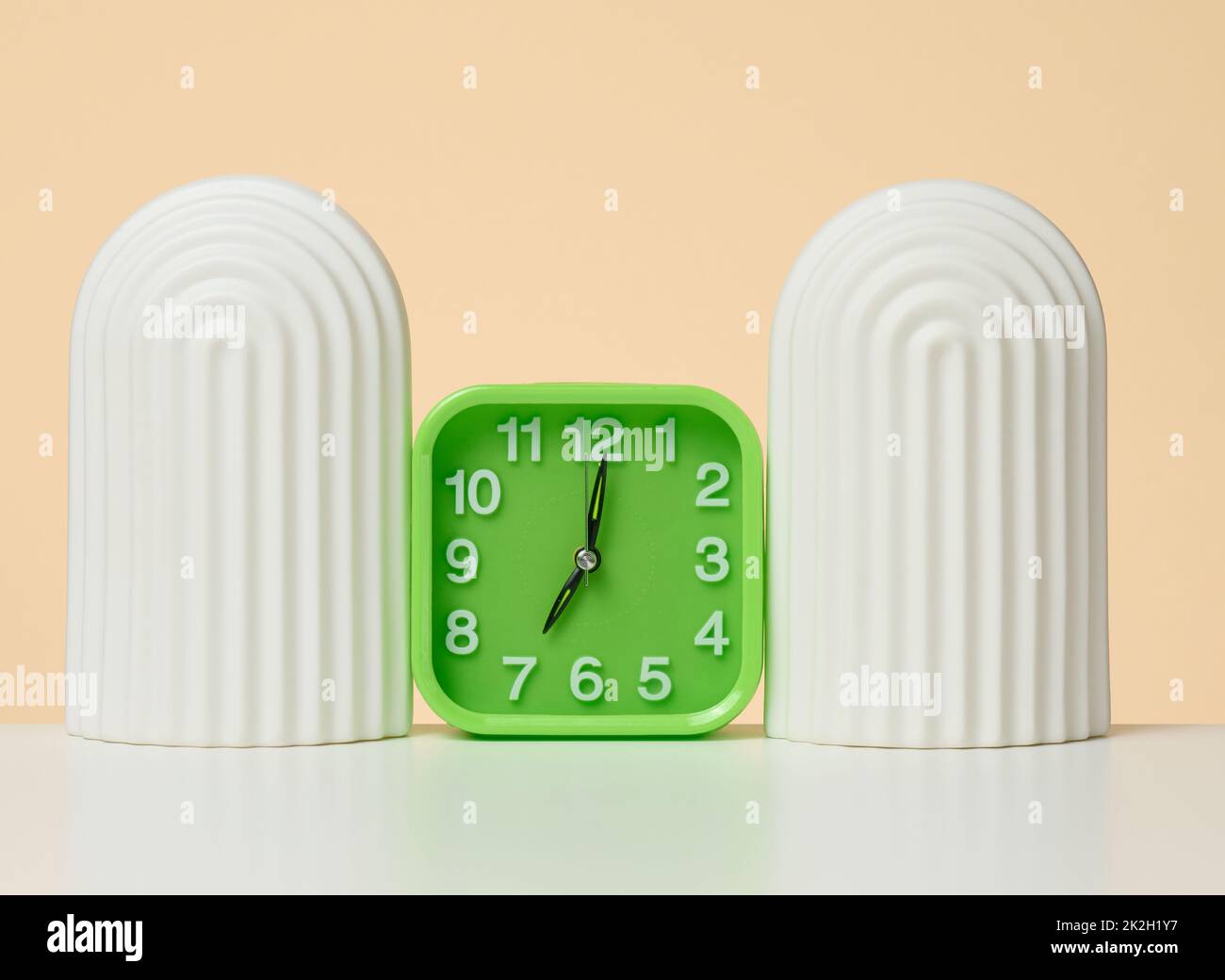 Square alarm clock on a white table. The time is seven in the morning. early rise Stock Photo