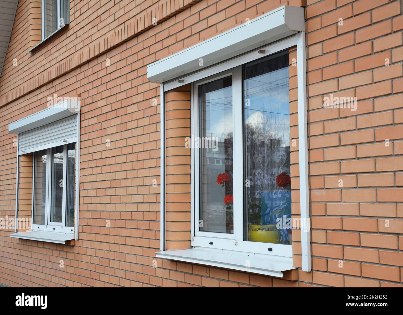 Rolling shutters house windows protection. Brick house with metal roller shutters on the windows Stock Photo