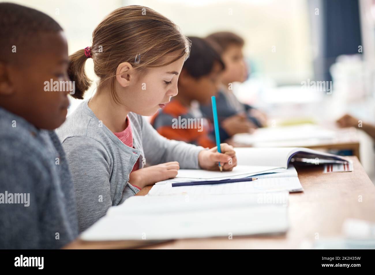 Shes a focused learner. Shot of an elementary school girl working alongside her peers in class. Stock Photo