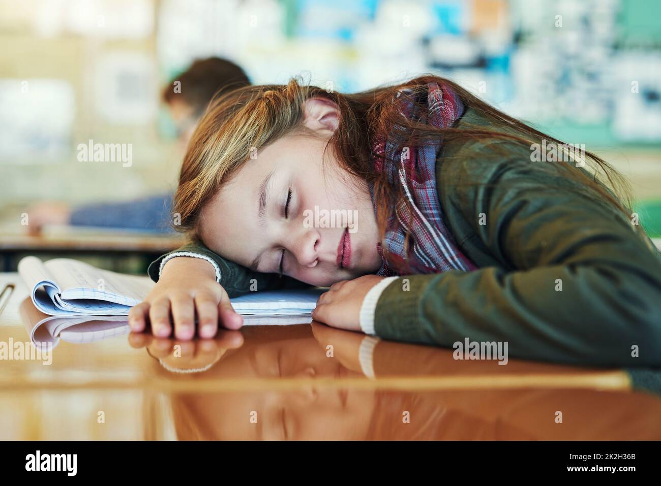 Shes refreshing her young mind. Shot of an adorable elementary schoolgirl taking a nap on her desk in class. Stock Photo
