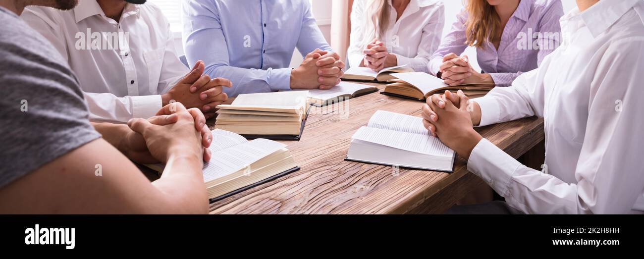 Group Of Young Multiethnic People Reading Bible Over Wooden Desk Stock Photo