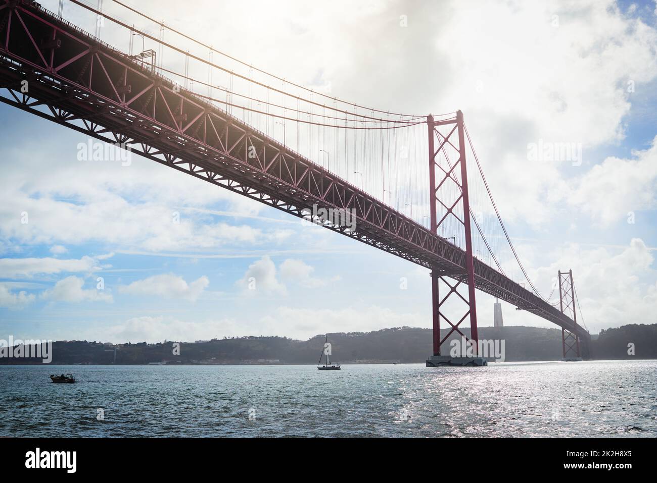 From one place to another. Low angle shot of a massive bridge over the ocean with clouds in the background outside during the day. Stock Photo