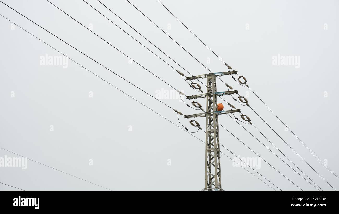 Low angle close-up view of the top part of an electricity distribution pylon and power lines Stock Photo