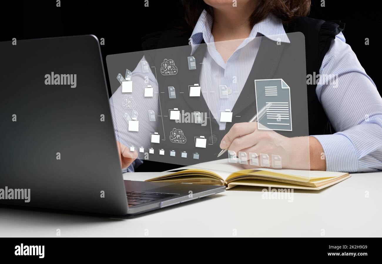 Woman sits at a table and works with a laptop. Document management ...