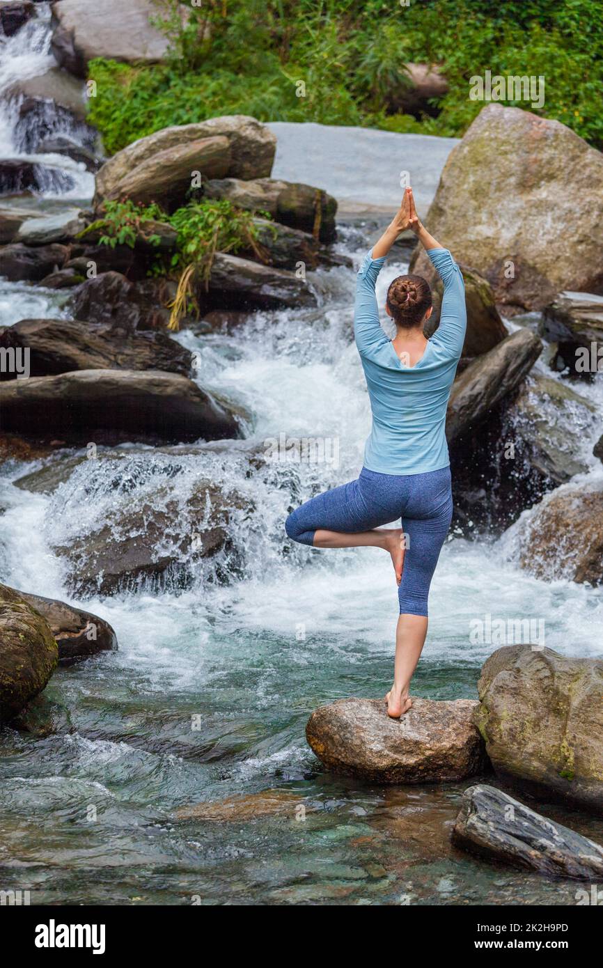 Woman in yoga asana Vrikshasana tree pose at waterfall outdoors Stock ...