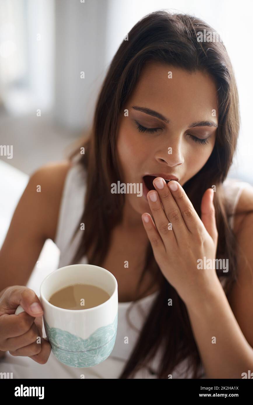 Waiting for the caffeine to kick in. a beautiful young woman yawning