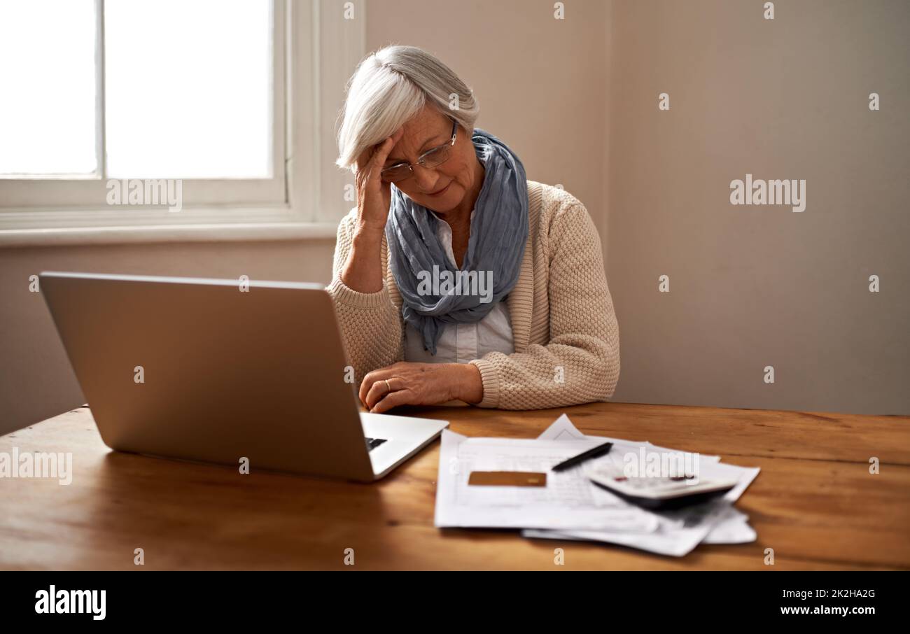 Retirement fund worries...An elederly woman sitting in front of her laptop looking stressed and worried. Stock Photo
