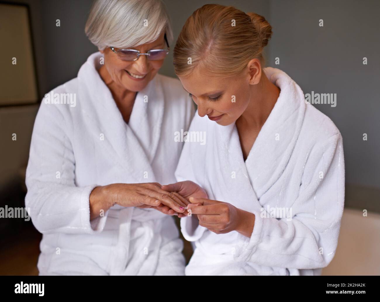 Making sure that her nails are perfect. Granddaughter paints her grandmothers nails. Stock Photo