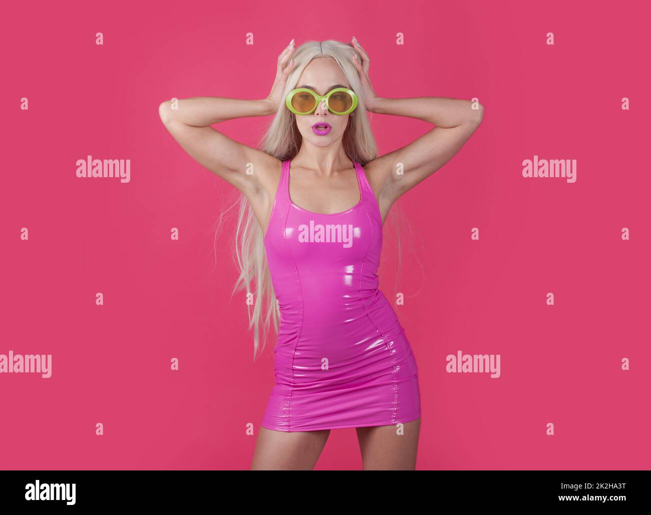 Pretty woman in pink latex dress and funny sunglasses. Sexy woman in provocative posing with long hair in a pink latex dress and sunglasses on Stock Photo