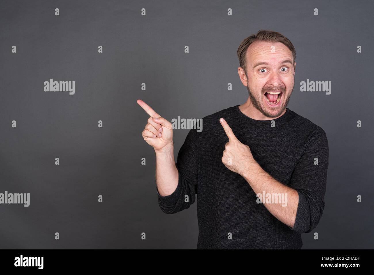 Portrait of blonde Caucasian man pointing fingers to copy space Stock Photo