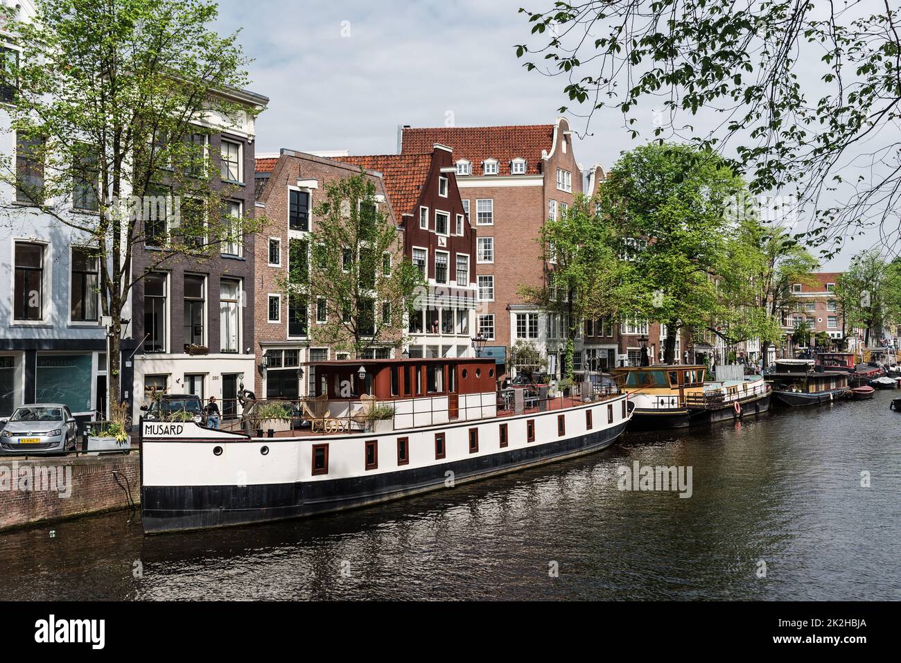 Amsterdam, Netherlands - May 7, 2022: Scenic view of canal with typical Dutch and boats houses in early morning Stock Photo