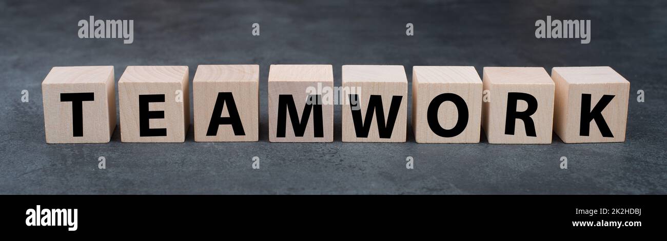 The word teamwork is standing on wooden cubes, dark background, working in a team, business concept, partnership Stock Photo