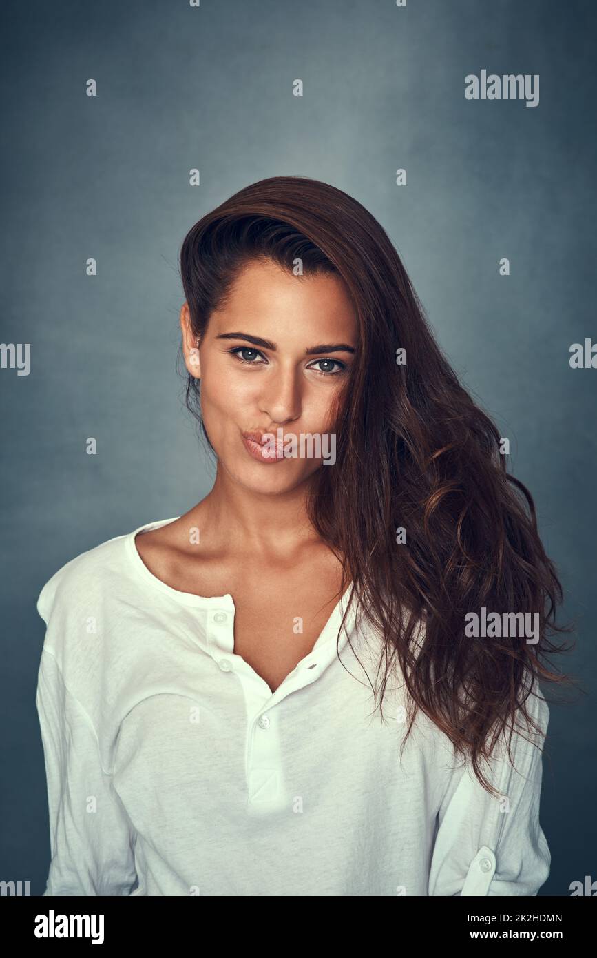 Pout it out. Portrait of a beautiful young woman pulling a funny face against a gray background in studio. Stock Photo