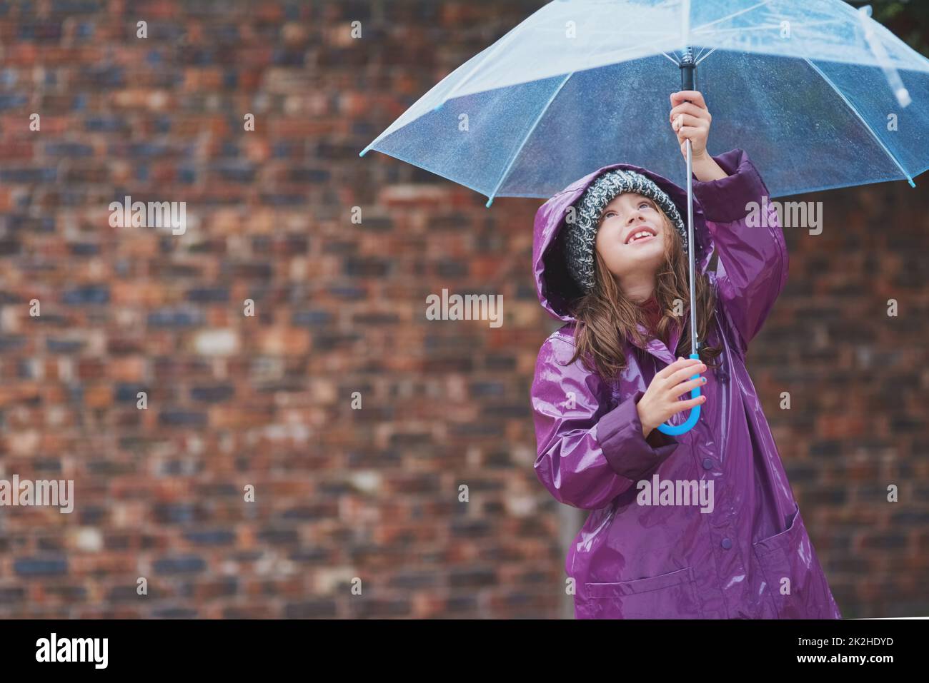 Its raining, its pouring.... Cropped shot of a little girl standing under an umbrella outside. Stock Photo
