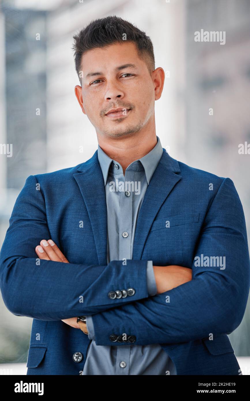 Business challenges dont kill me ambition. Shot of a handsome young businessman standing alone in the office with his arms folded. Stock Photo