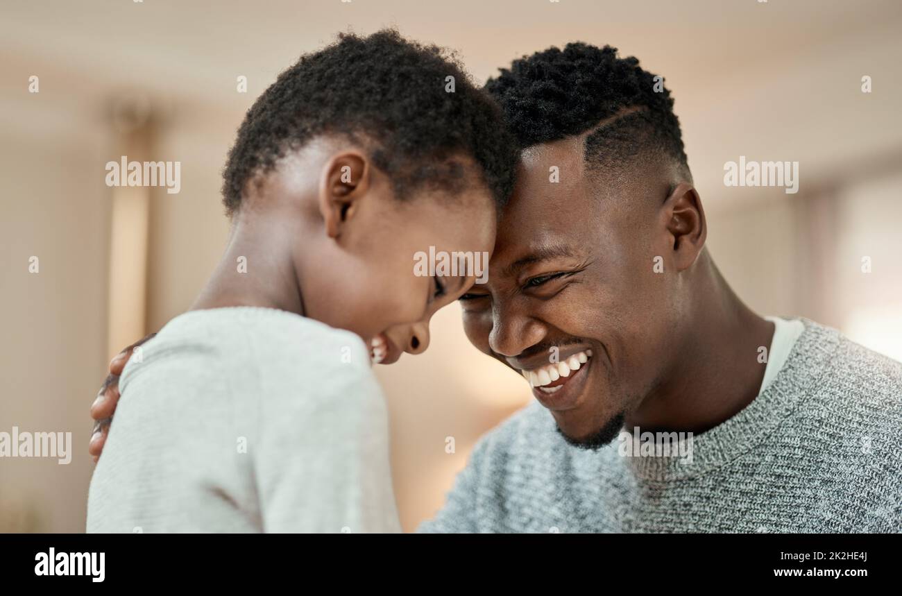 Im so proud of you. Cropped shot of a handsome young man and his son standing face to face with their heads touching in the living room at home. Stock Photo