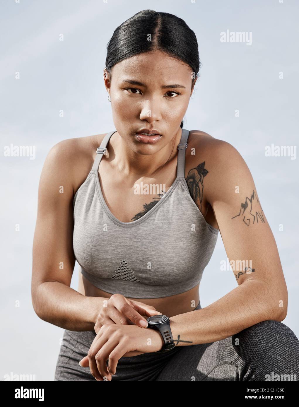 This watch dont just tell the time. Shot of a sporty young woman checking her smartwatch while exercising outdoors. Stock Photo