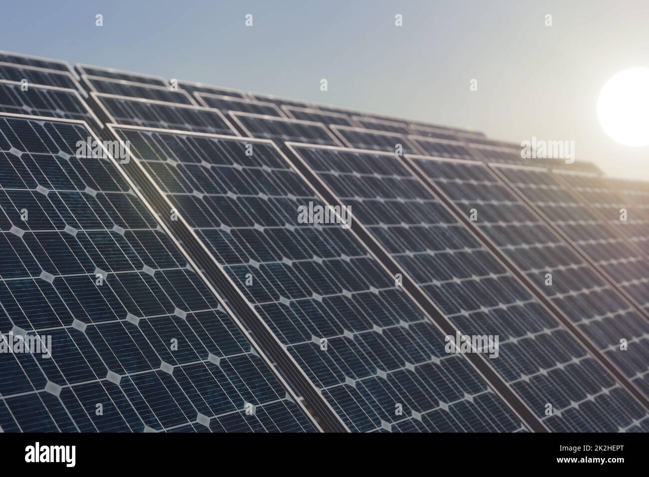 Solar power plant against the rising sun, selective focus on the first solar panel. Stock Photo