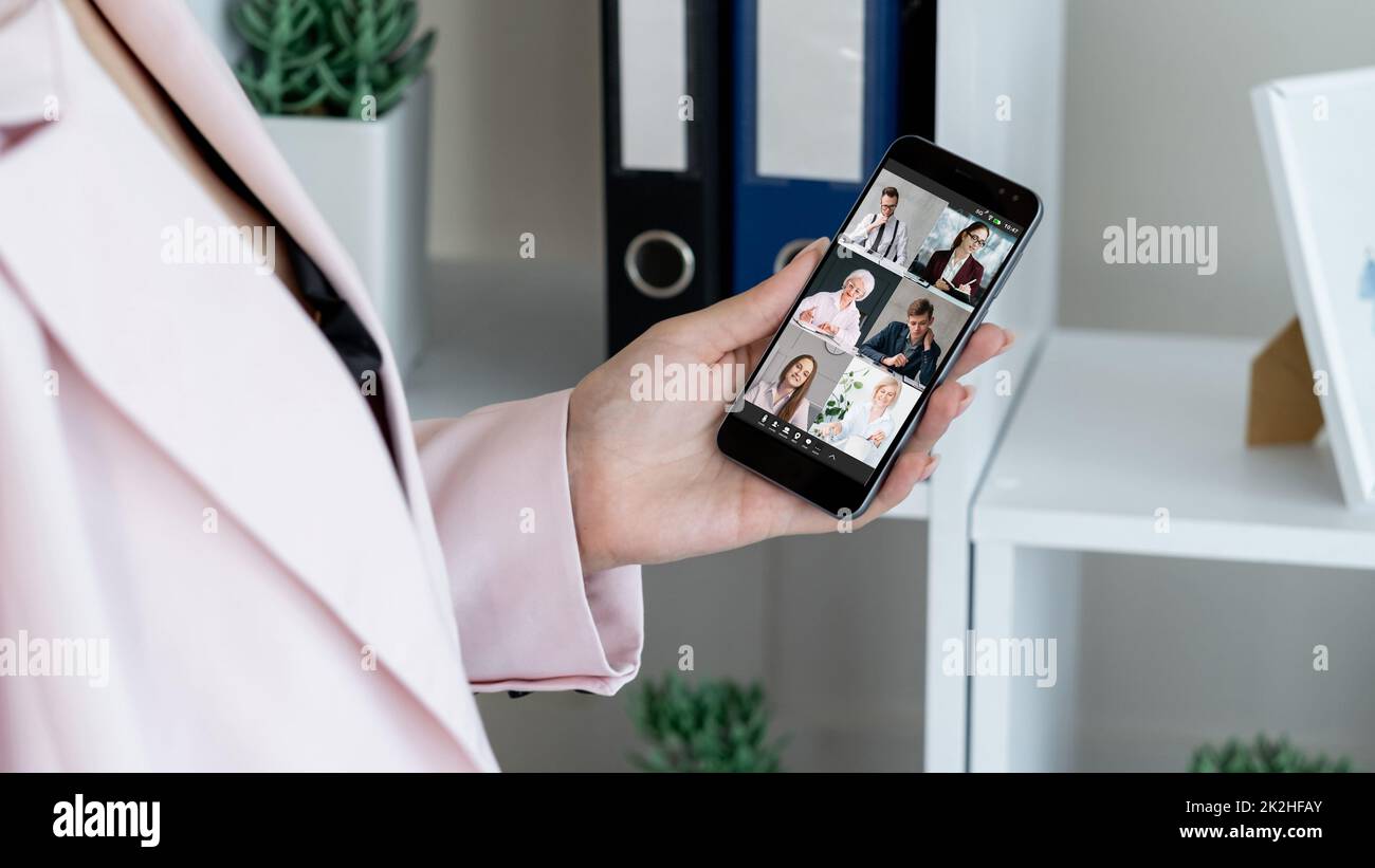 Mobile video call. Business teleconference. Virtual interview. Communication technology. Woman cooperating online with team on smartphone screen. Stock Photo