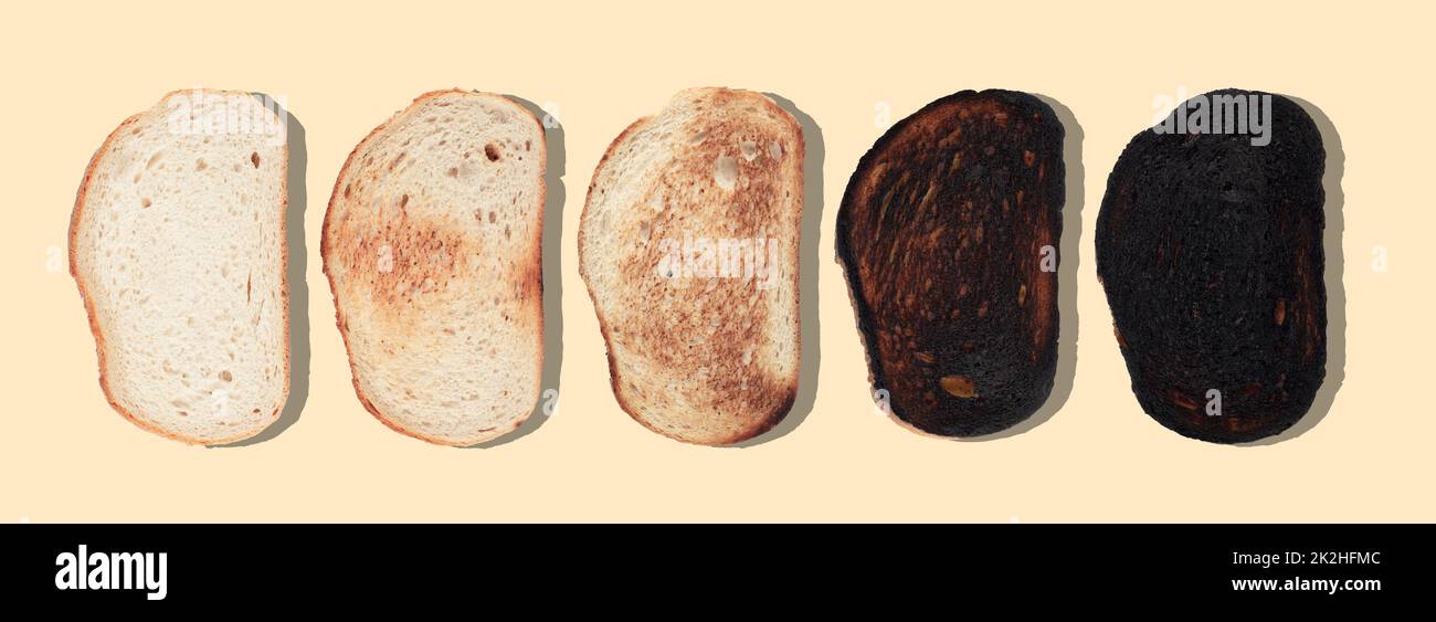 slices of bread at different stages of toasting with last one completely burnt on brown background Stock Photo