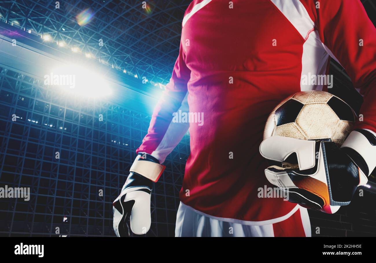 Goalkeeper holds the ball in the stadium during a football game Stock