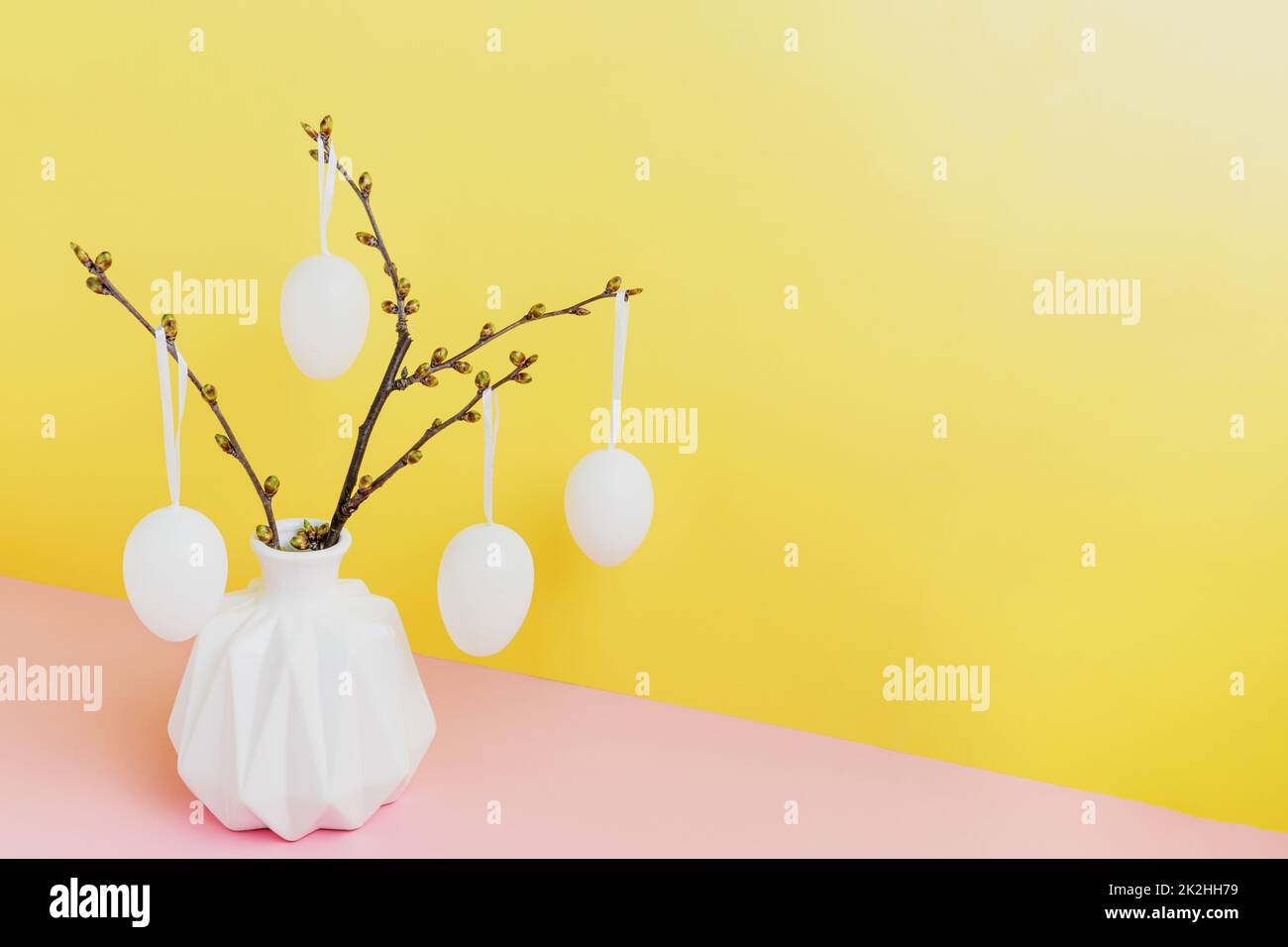 Happy Easter holiday, coming spring. Branches in white vase, hanging eggs Stock Photo