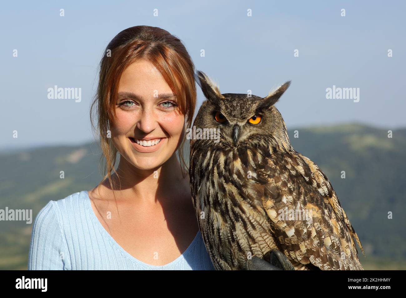 Happy falconer with an eagle owl looking at camera Stock Photo