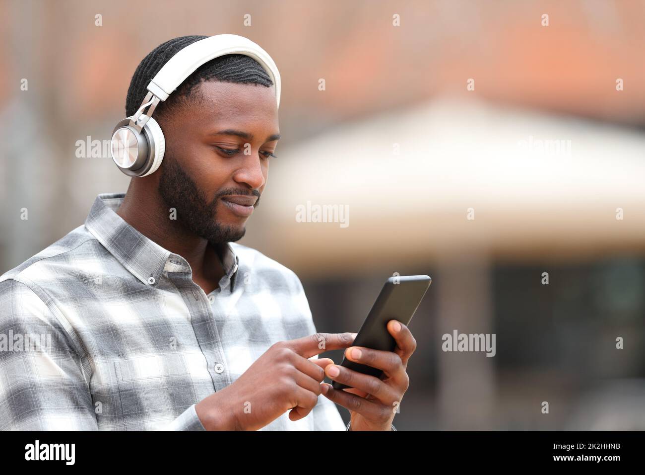 Man with black skin listening to music walks in the street Stock Photo