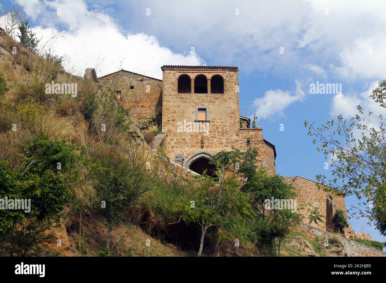 A traditional rock house on the cliff of a mountain with olive trees in