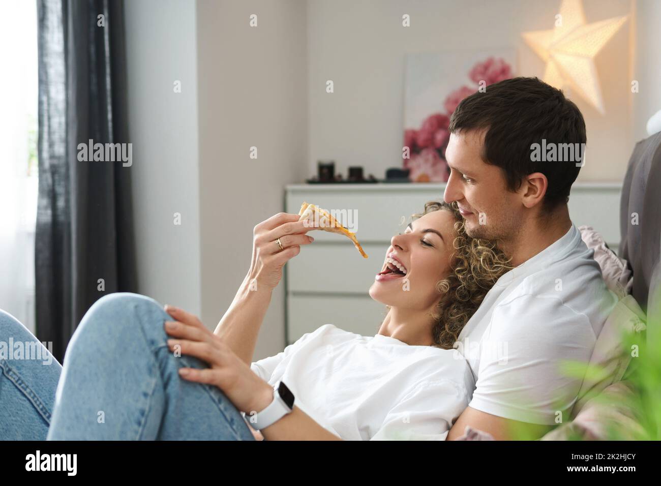 Lazy and happy couple eating pizza on the bed Stock Photo