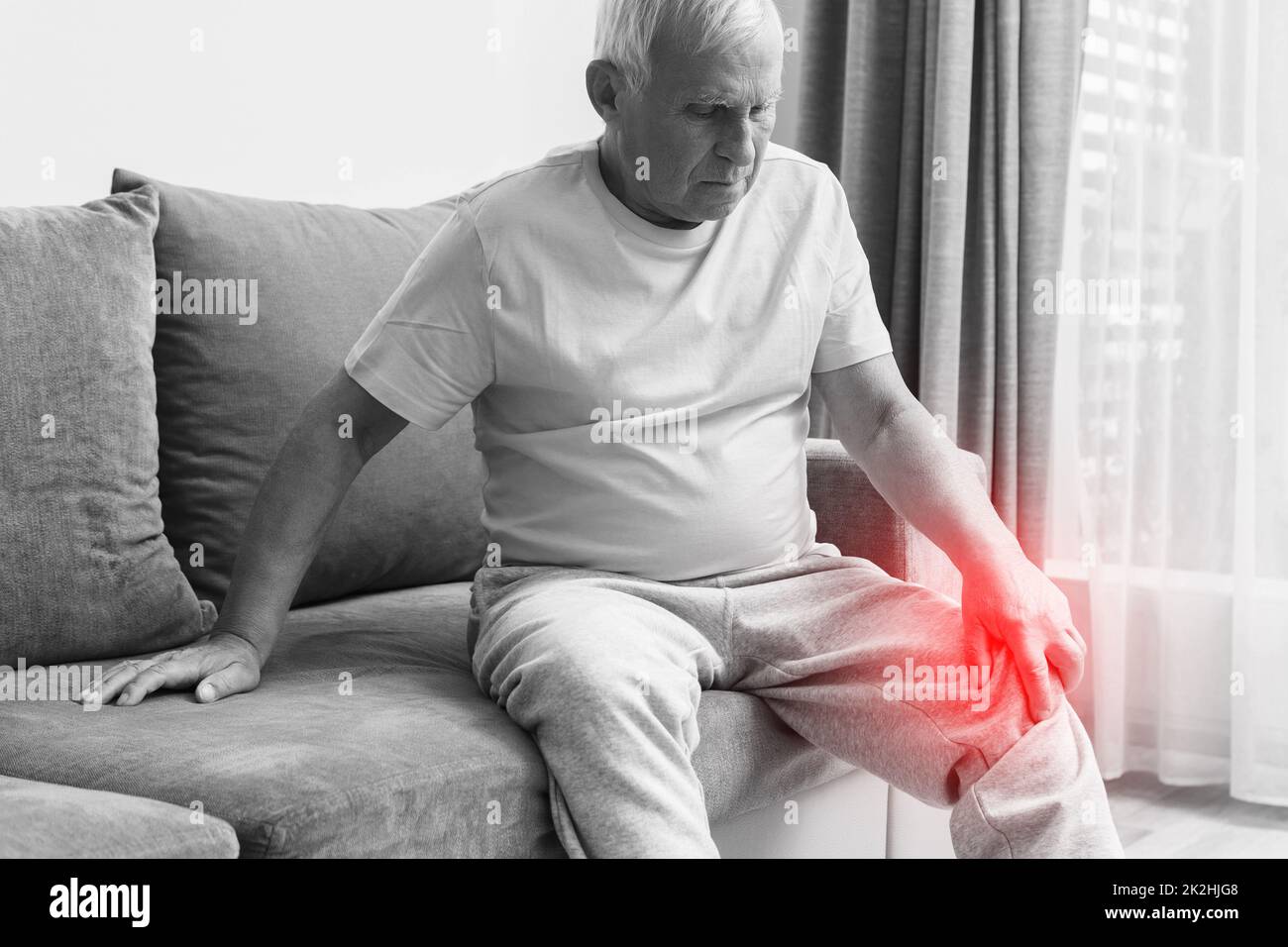 Senior man suffering from pain in his knee at home Stock Photo - Alamy