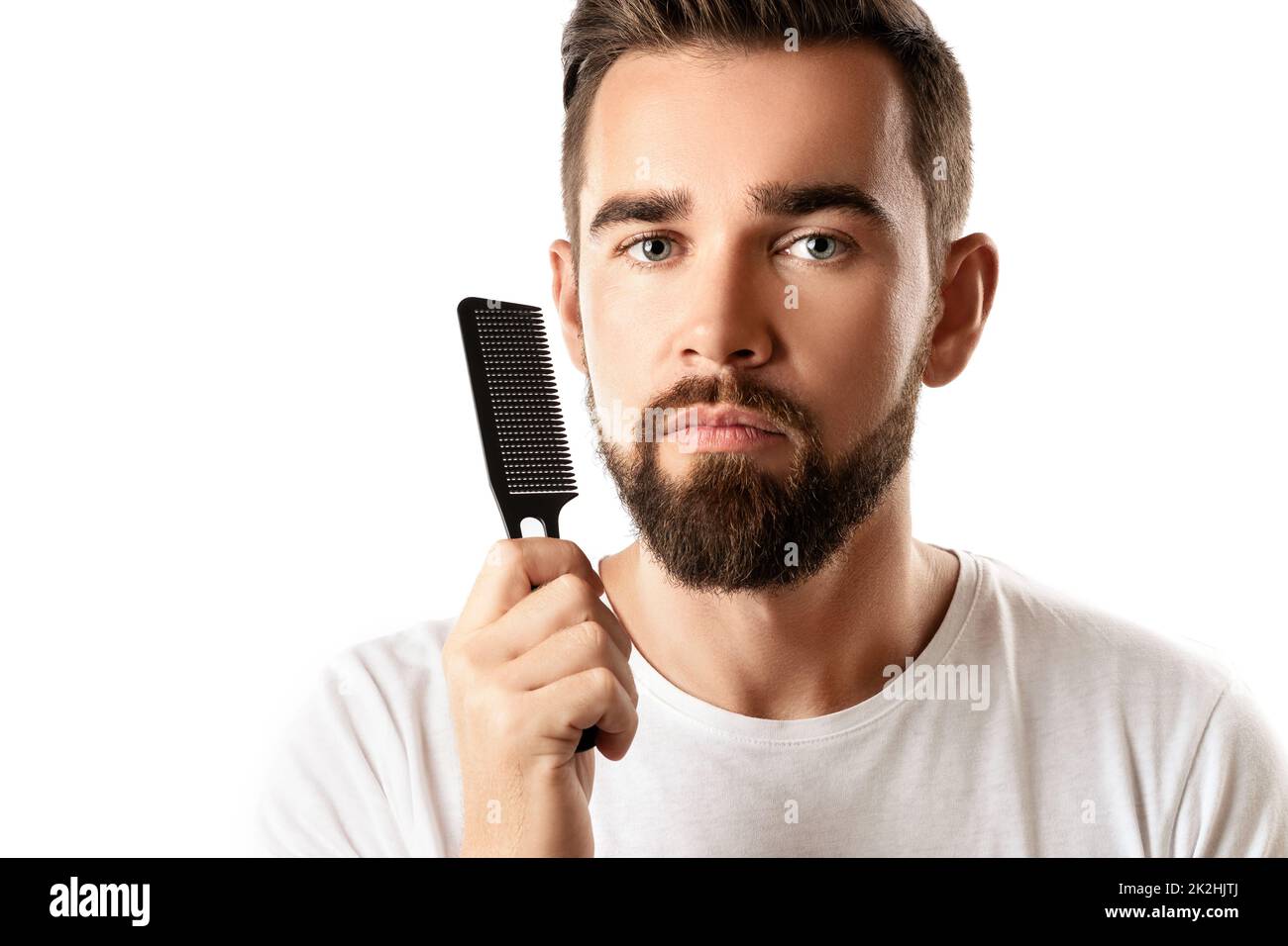 Handsome well groomed man combing his beard Stock Photo