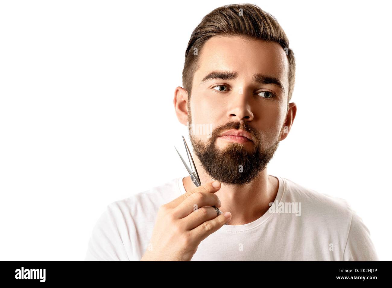 Handsome man trimming his beard with a scissors Stock Photo